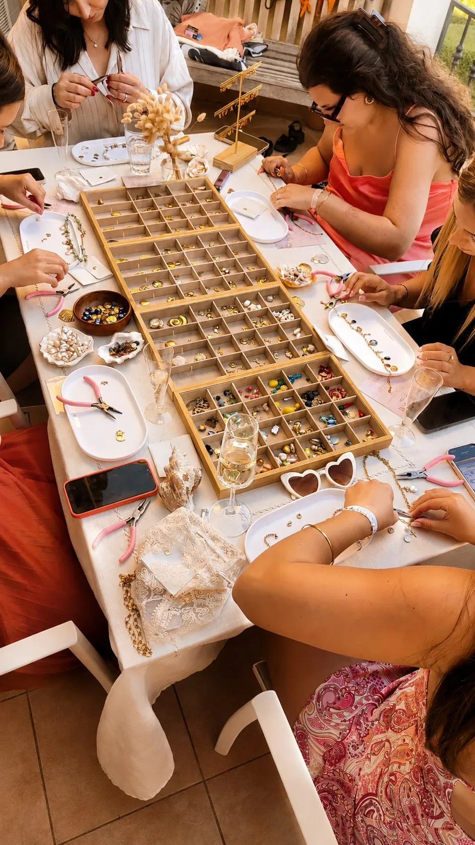 Autour de la table d’atelier : les plateaux de charms, les pinces et les mains au travail