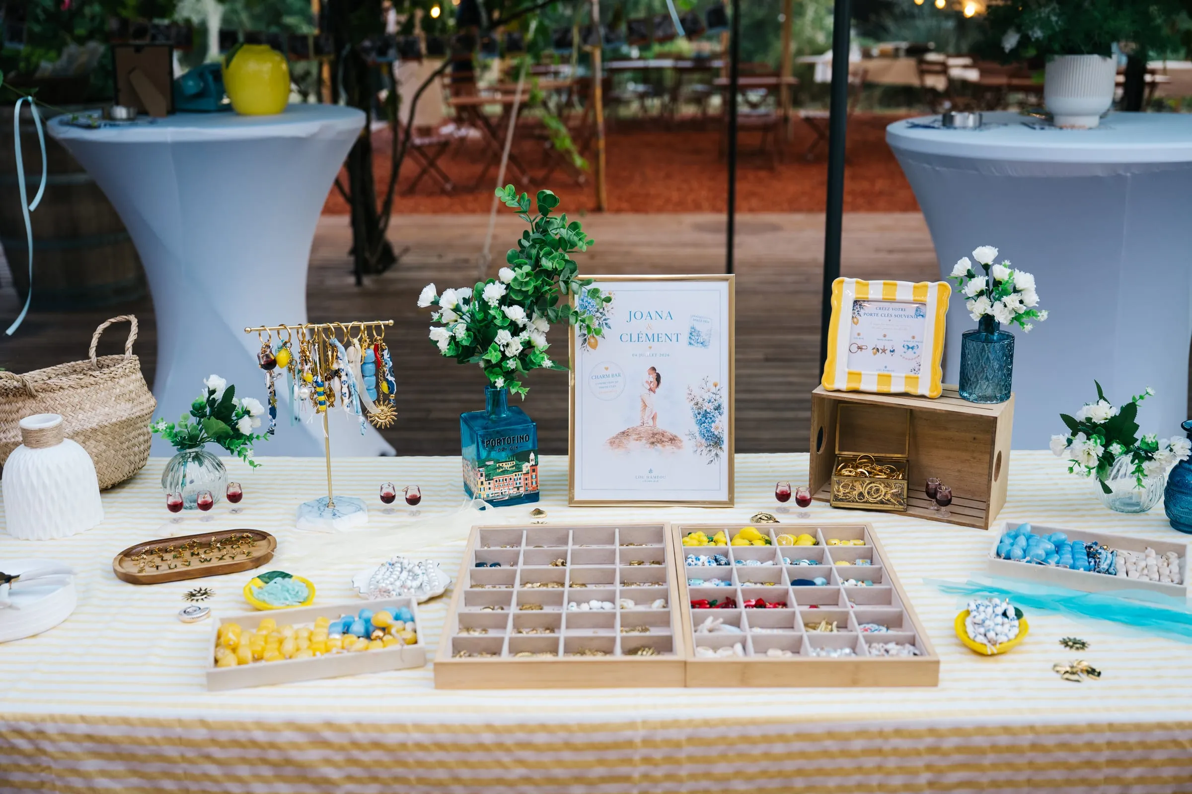 Charm Bar installé en extérieur : longue table nappée, plateaux de charms, présentoirs en bois et papeterie personnalisée