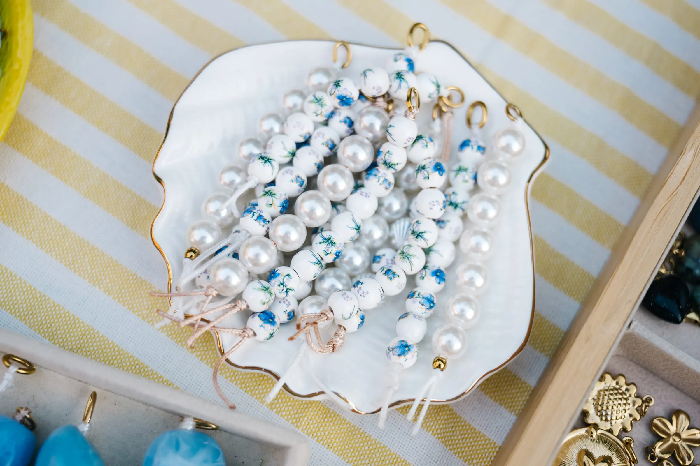 Grigris de perles terminés, posés sur une assiette en forme de coquille