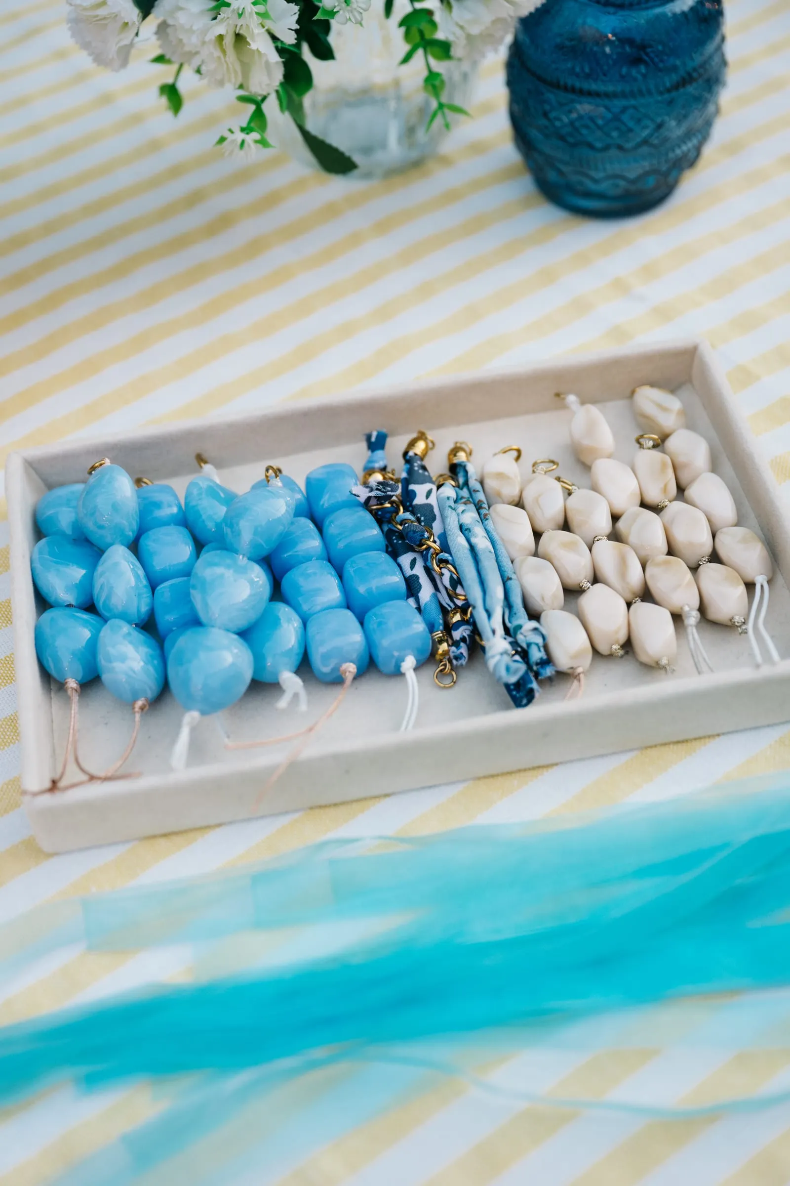 Perles bleues et rubans azur disposés sur une nappe rayée