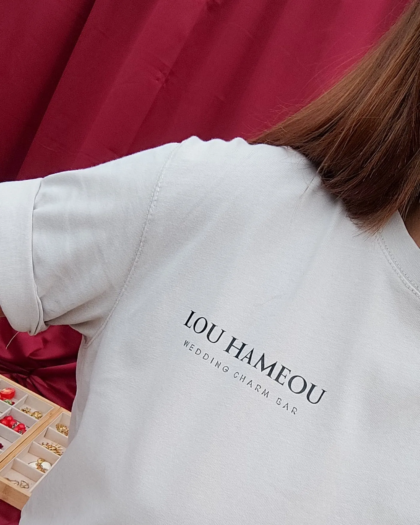 De dos, en t-shirt Lou Hameou Wedding Charm Bar, devant la table de charms