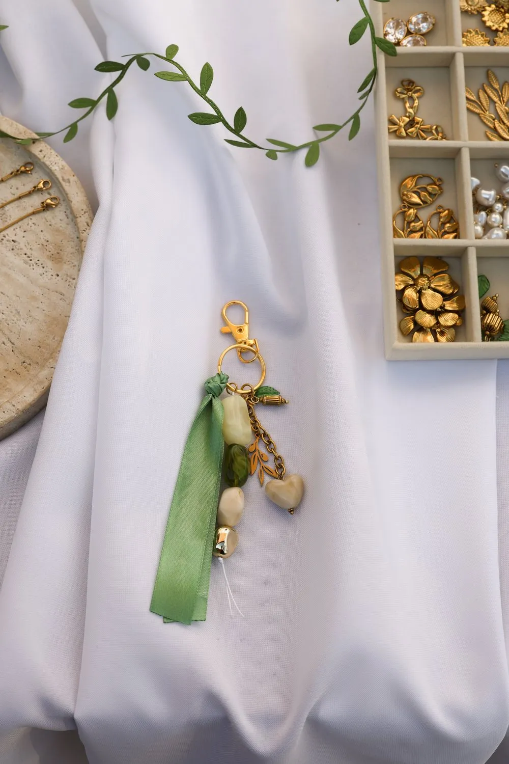 Porte-clés en cours de composition, ruban de gros-grain vert sur le drapé blanc